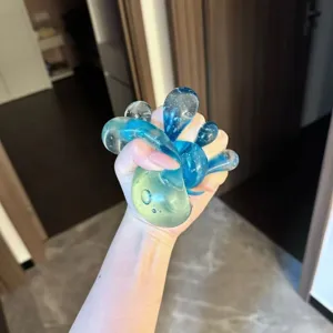 Detailed close-up of a hand squeezing a transparent blue and yellow maltose ice cube toy