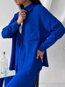 Primo piano della camicia blu a maniche lunghe con tasca e pantaloni larghi coordinati.