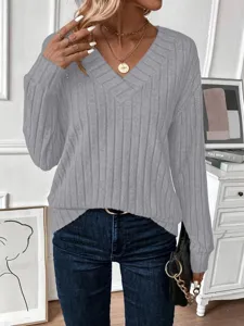 Close-up of a grey V-neck ribbed knit sweater styled with blue denim jeans and jewelry.