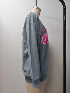 Detaillierte Seitenansicht eines grauen Cord-Sweatshirts mit rosa Buchstabendruck