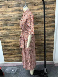 Side view detail of a vibrant orange geometric print midi shirt dress with waist belt