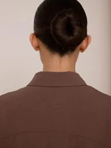 Primo piano della vista posteriore del colletto di un cardigan marrone da donna con trama fine.