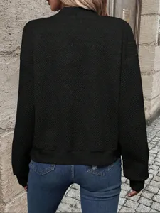 Detailed back view of women's black textured knit bomber jacket in a street setting
