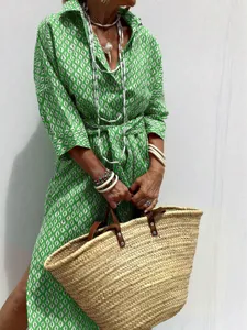Close-up of a green patterned women's shirt dress paired with a woven straw basket bag.