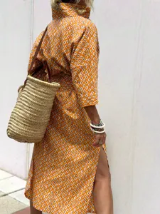 Side view of orange geometric pattern shirt dress with side slit and straw bag