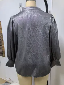 Detailed back view of a silver metallic long-sleeve satin blouse shown on a studio mannequin