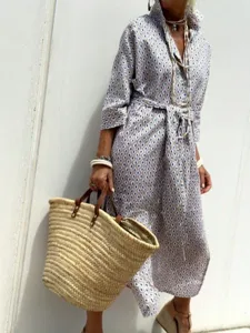 Bohemian geometric pattern shirt dress with waist tie and straw bag accessory.