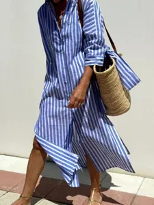 Detail of blue and white striped button-down shirt dress with side slits and straw bag