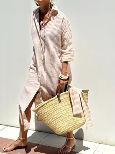 Side view detail of a striped midi shirt dress styled with a woven straw basket bag