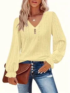Detailed view of yellow eyelet V-neck top with ruffled lantern sleeves and button trim