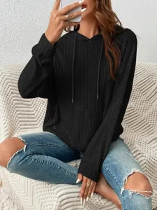 Detail of black ribbed hooded sweatshirt featuring a front kangaroo pocket and drawstrings