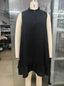 Detail view of black sleeveless cotton-linen dress featuring button collar and ruffled hem.