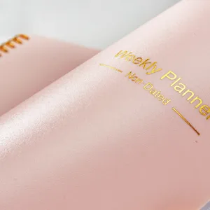 Dettaglio di un'agenda settimanale in ecopelle rosa con scritte in lamina d'oro.