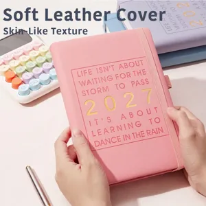 Gros plan d'un agenda rose A5 2027 avec texture cuir souple et marquage doré