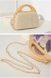 Detail shot of a straw woven evening bag with floral embroidery and wooden handle