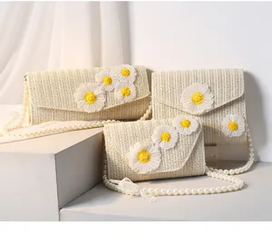 Dreiteiliges Strohtaschen-Set mit Gänseblümchen-Stickerei und eleganten Perlenketten.