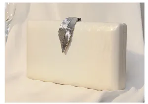 Detailansicht des eleganten silbernen Blattverschlusses einer cremefarbenen Abendtasche