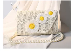 Nahaufnahme der Gänseblümchen-Stickerei und Strohgeflecht-Textur auf Handtasche.