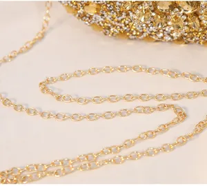 Makrodetail des eleganten goldfarbenen Metallkettenriemens an der diamantbesetzten Clutch
