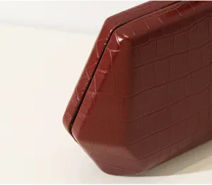 Nahaufnahme der burgunderroten Abendtasche mit Krokodilmuster und geometrischer Form