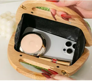 Detailansicht der grünen Stroh-Abendtasche innen mit schwarzem Futter und Holzgriff