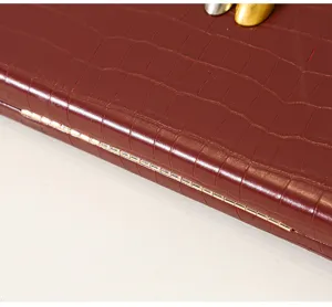 Primer plano del detalle de la bisagra del bolso de fiesta de PU rojo vino cocodrilo.