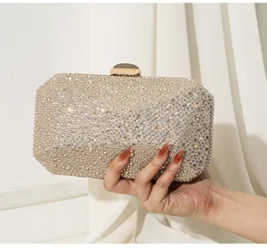 Nahaufnahme einer luxuriösen funkelnden goldenen Abendtasche mit Strasssteinen in der Hand