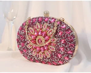 Detailansicht einer eleganten Abendtasche mit rosa Kristallblume und goldenem Griff
