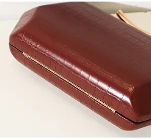 Detailansicht der Kroko-Prägung und des goldfarbenen Metallscharniers der burgunderroten Clutch