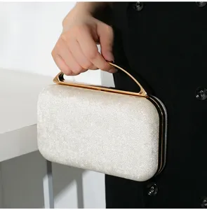 Detailansicht einer eleganten glitzernden silbernen Abendtasche mit goldenem Metallgriff.