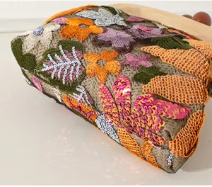 Macro detail view of vibrant handmade floral embroidery and sequins on an evening bag