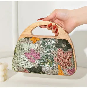 Detail of hand-held embroidered evening bag featuring colorful floral sequins and wood handle.