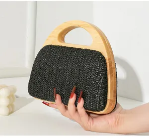 Detailansicht einer schwarzen gewebten Abendtasche mit Massivholzgriff, von Hand gehalten