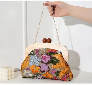 Detailed view of an embroidered straw evening clutch with sequins and wood handle