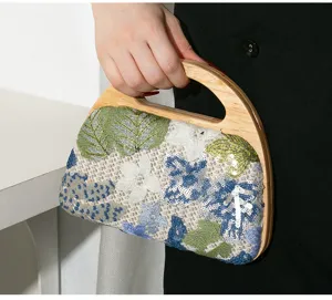 Handheld detail of women's evening bag with wood handle and floral sequin embroidery.