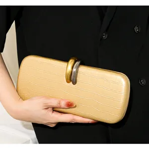 Primer plano de un bolso de mano dorado con textura de cocodrilo y cierre metálico.