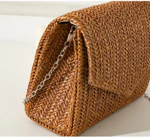 Detailaufnahme der braunen Strohhandtasche mit eleganter Webstruktur und Metallkette