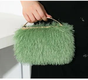 Detailaufnahme einer grünen Abendhandtasche mit Fransen und elegantem goldenen Metallgriff