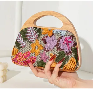 Detailed view of women's evening clutch with wooden handle and floral sequins embroidery