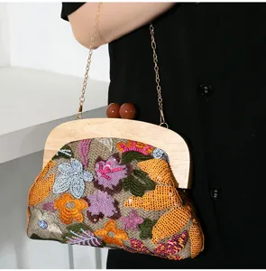 Detailed view of handmade embroidered evening clutch with colorful sequins and wooden handle.
