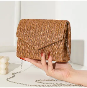 Detailansicht einer stilvollen braunen gewebten Clutch mit einem silbernen Kettengurt
