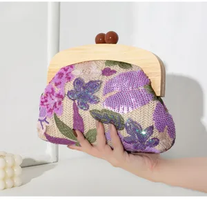 Close-up of handmade embroidered sequin straw evening bag with elegant solid wood handle