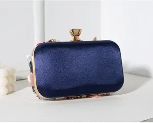 Vista detallada del bolso de satén azul marino con flores de cuentas hechas a mano