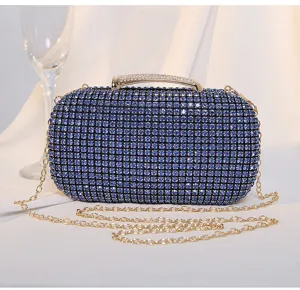 Nahaufnahme einer blauen Abendtasche mit Strasssteinen und goldener Kette.