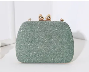 Nahaufnahme einer salbeigrünen Glitzertasche mit doppelten herzförmigen Goldverschlüssen.