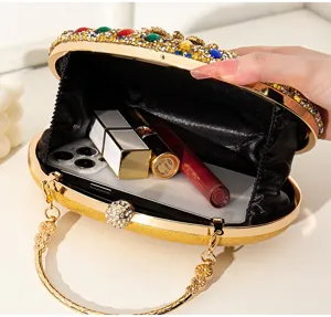 Vue détaillée de l'intérieur d'une pochette de soirée dorée avec strass et accessoires.