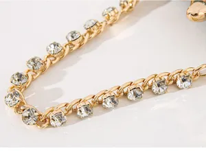Detailaufnahme des goldfarbenen Kettenriemens mit glitzernden Strasssteinen für Abendtaschen