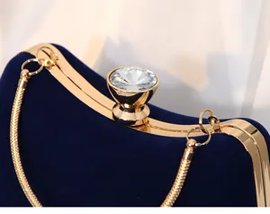 Detailansicht einer luxuriösen blauen Samt-Abendtasche mit Goldrahmen und Kristall.