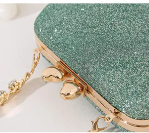 Nahaufnahme grüne Glitzer-Abendtasche mit goldener Herzschließe und Kristallkette