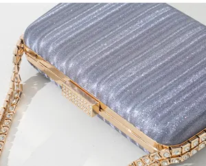 Detail eines silbernen Glitzer-Abend-Clutch mit Strass-Verschluss und Goldkette